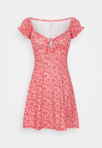 Czerwona sukienka w kwiaty ma krótkie bufiaste rękawy, dekolt w kształcie litery V z wiązaniem, dopasowaną górę i rozkloszowany dół. Materiał ma gładką, lekką teksturę.