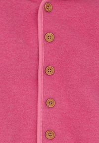 Roze vilt kledingstuk met een knoopsluiting voorzien van zes ronde houten knopen en een contrasterende roze bies langs de randen.