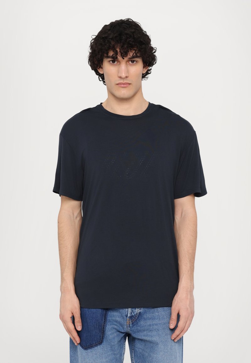 T-shirt bleu marine foncé avec un col rond, des manches courtes et un motif logo subtil sur le devant. Fabriqué en tissu doux et léger.