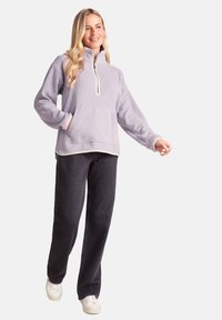 Light purple fleece half-zip pullover with a front pocket and contrasting cream trim; paired with dark jeans and white sneakers.