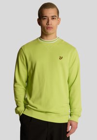 Felpa verde lime con colletto tondo e strisce bianche, caratterizzata da un logo giallo ricamato sul petto. Realizzata in tessuto morbido.