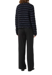 Gestreifter, schwarz-blauer, strukturierter Strickpullover mit einem verkürzten Design, kombiniert mit hoch taillierten schwarzen Hosen. Einfache, gerade Silhouette.