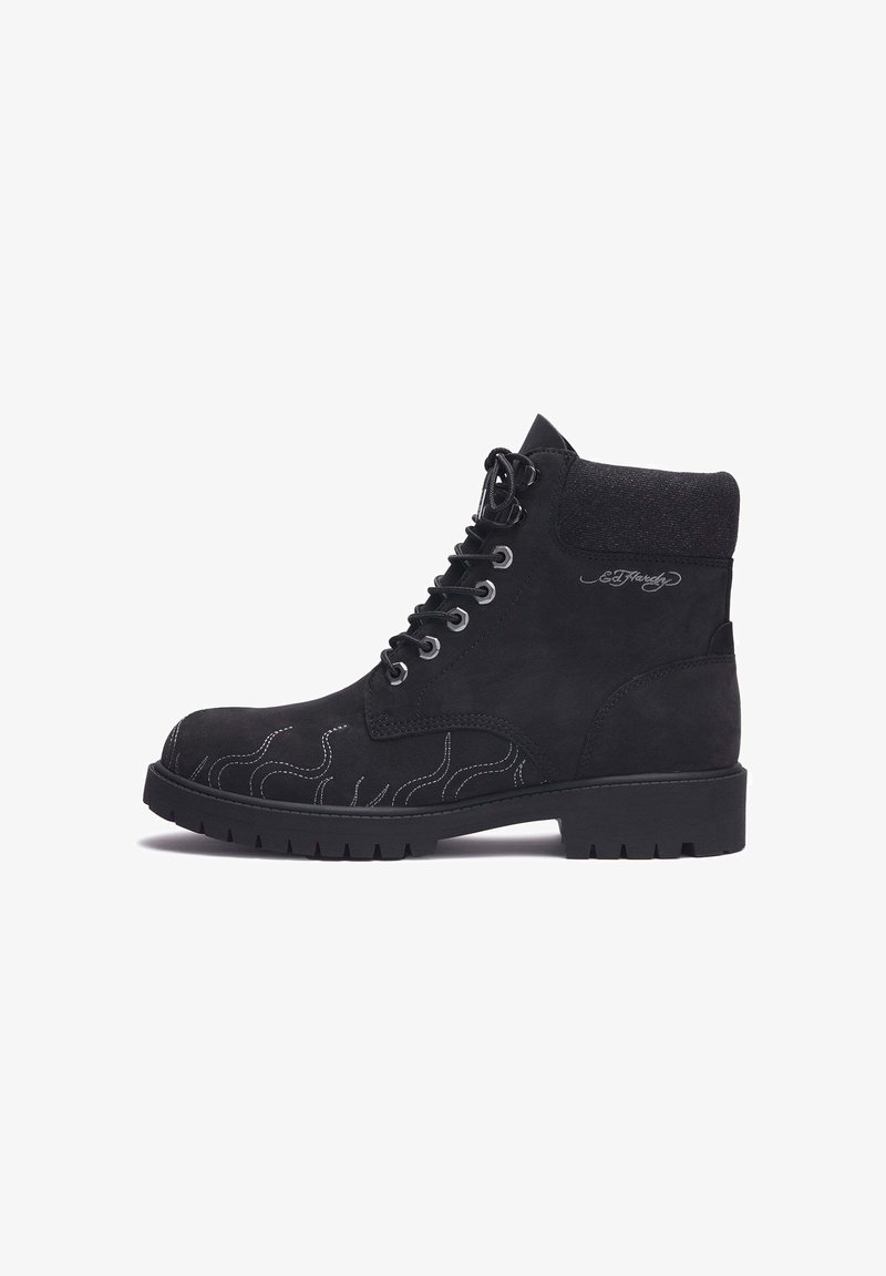 Schwarze Wildleder-Stiefelette mit weißer Flammenstickerei, runder Spitze, Metallösen und einer strukturierten Gummisohle mit Profil.