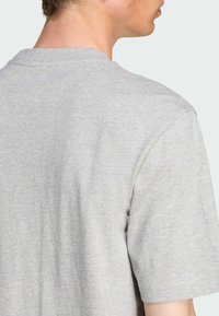Lys grå T-shirt lavet af blød bomuld. Har en klassisk rund halsudskæring og korte ærmer, med en glat tekstur og minimalistisk design.