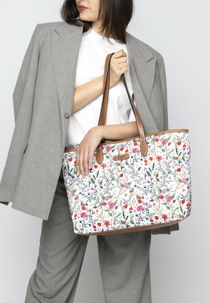 Floral-patterned tote bag with a white background, featuring multicolored flowers and brown leather handles and accents.