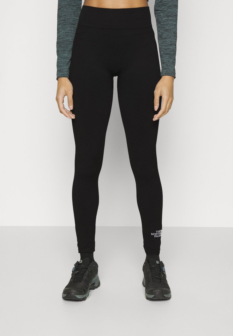 Leggings neri con una vita alta, realizzati in un materiale liscio e elastico. Presentano un piccolo logo bianco sulla caviglia sinistra.