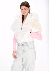 Tęczowa krótka kurtka puchowa z zamkiem z przodu, puszystym białym kapturem i krótkimi, puchowymi rękawami. Nosi się ją na długim różowym topie z długim rękawem.