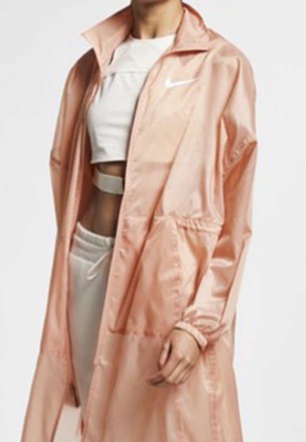 Rosa nylon vindjacka med hög krage, framfickor och elastiska muddar. Kombination med en vit topp och träningsbyxor.