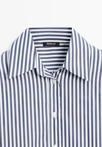 Camicia a righe blu e bianche con colletto classico, chiusura a bottone e texture liscia. L'etichetta indica "Massimo Dutti, Made in Portugal."