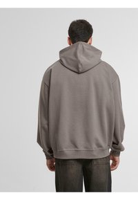 Grå hættetrøje med løs pasform, drop-skuldrer og ribbet manchetter. Blødt stof og minimalistisk design.
