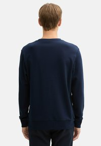 Dunkelblaues Sweatshirt mit langen Ärmeln, gerippten Bündchen und Rundhalsausschnitt. Glatte Textur, einfaches Design und keine sichtbaren Logos oder Muster.