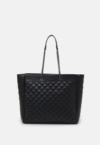 Sac cabas noir matelassé avec des anses en chaîne, présentant une silhouette structurée et des accents en cuir lisse. Design épuré sans logo apparent.