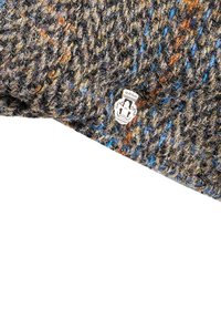 Wool cap in earthy tones with brown, orange, and blue flecks. Features a textured pattern and a small silver branded emblem on the side.
