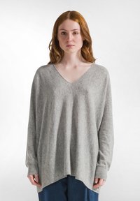 Hellegrau oversized Pullover mit V-Ausschnitt, langen Ärmeln und lockerer Passform. Weicher Stoff mit gerippten Bündchen und leicht abgerundetem Saum.