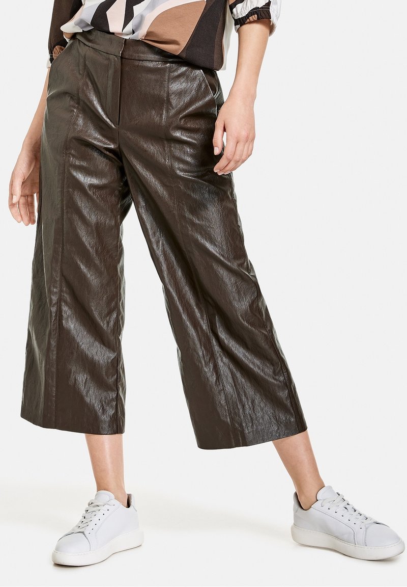 Bruna fusk läder culottes med en glansig finish, med vida ben, framsömmar och hög midja, i kombination med vita sneakers.