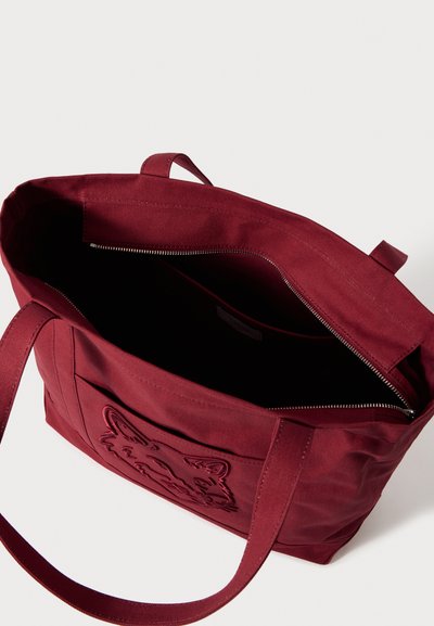 Vyno raudonos spalvos drobinis pirkinių krepšys su užtrauktuku viršuje, priekyje su reljefiniu gyvūno piešiniu ir tvirtomis audinio rankenėlėmis. Vidus yra juodos spalvos.