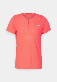 Camisa atlética de manga corta de Nike en coral brillante con un cuello de media cremallera, que presenta un logo y un patrón texturizado en toda la prenda.