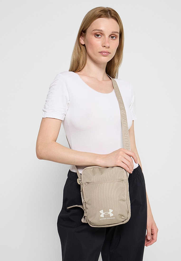 Sacoche crossbody Under Armour en kaki avec un tissu texturé, une sangle ajustable et une poche zippée à l'avant avec un détails de logo.