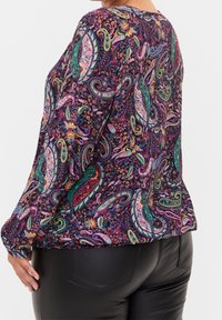 Blusa a maniche lunghe multicolore con motivo paisley su sfondo viola scuro, con orlo arrotondato e vestibilità ampia.