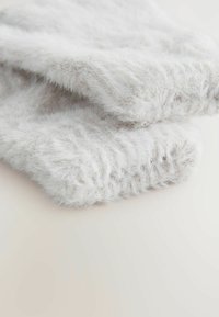 Blødt, hvidt, fuzzy strikstof foldet tæt sammen, som viser detaljeret tekstur og fiber på en neutral lys baggrund.