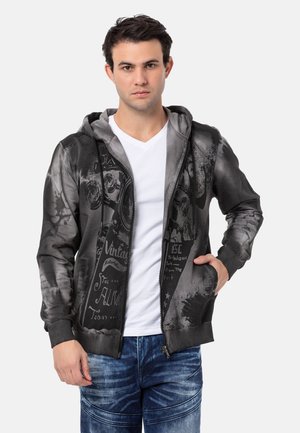 Schwarze und graue Zip-Up-Hoodie mit einem grafischen Druck im Vintage-Stil, Kordelzugkapuze und seitlichen Taschen. Weicher Stoff.