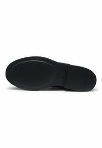 Musta kenkäpohja, jossa on hienot vaakaurat kantapäässä ja pallon alueilla, brändin kohokuviointi lähellä kaarta, sileät pyöristetyt reunat.