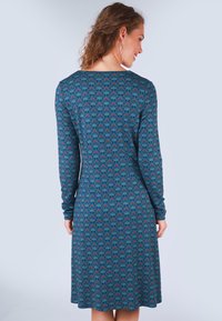 Langärmliges Kleid in Teal mit einem floralen Muster in Rot und Dunkelblau. Weiches Strickgewebe, A-Linien-Silhouette, bis zur Mitte der Waden reichend.