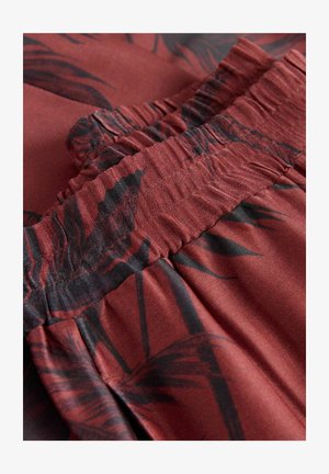 Bordeaux stof met een gladde textuur heeft zwarte palmbladeren patronen en een geplooide elastische tailleband langs de bovenrand.