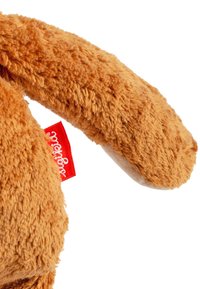 Plush toy with soft, textured, orange fur. Features a curved ear and a small red brand label. Tail has a rounded shape.