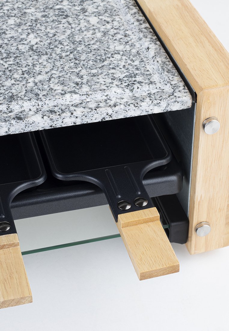 Gril à raclette avec un plateau en granit, cadre en bois, plaques de cuisson noires et poignées en bois. Présente des surfaces lisses et des accents en métal.