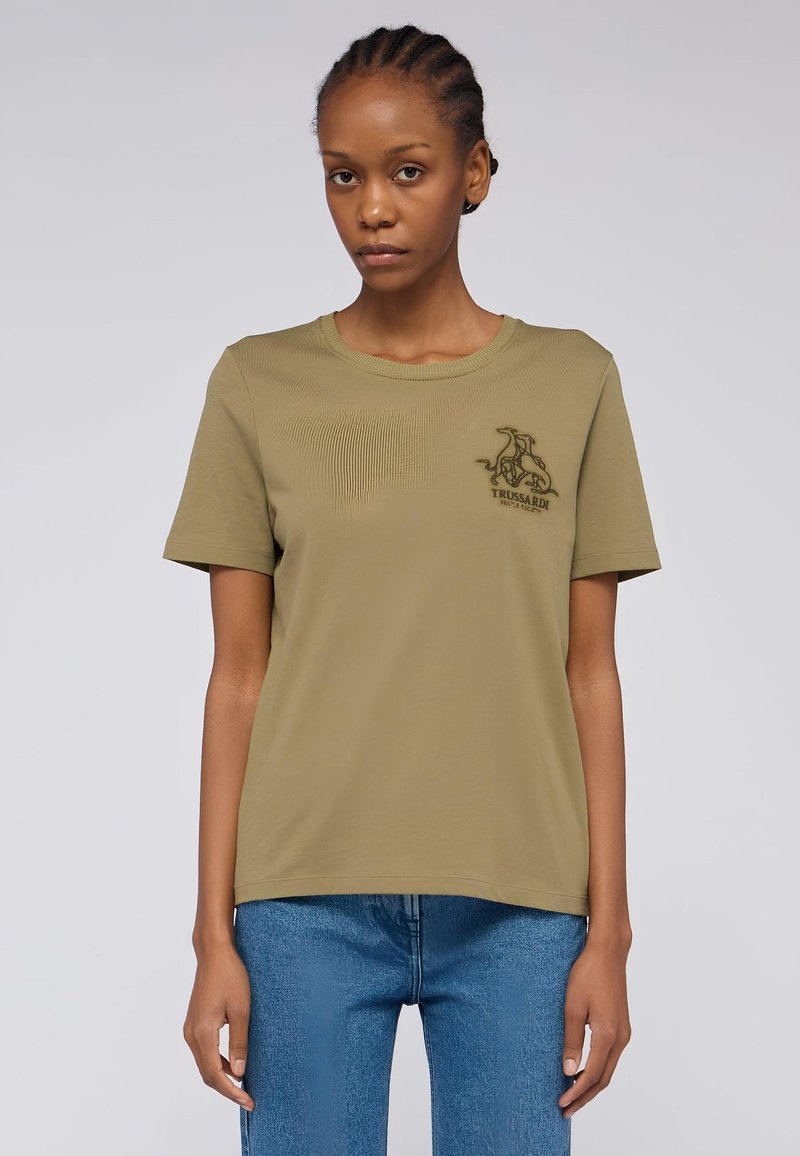 Olivgrünes T-Shirt mit kurzen Ärmeln aus weicher Baumwolle, das auf der Vorderseite über strukturierte diagonale Linien und ein gesticktes Logo auf der Brust verfügt.