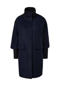 Manteau bleu marine foncé avec col côtelé haut, manches trois-quarts et poches à rabat, avec poignets en maille côtelée s'étendant à partir des manches.