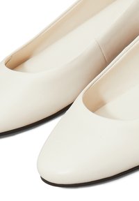 Bailarinas de punta puntiaguda en suave cuero blanco con textura lisa y diseño de corte bajo. La suela exterior es oscura, proporcionando contraste con la parte superior.