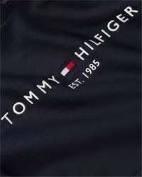 Tamsiai mėlyna medvilninė sportinė maikė su baltais siuviniais "TOMMY HILFIGER" ir logotipu, su "EST. 1985" po prekės ženklu.