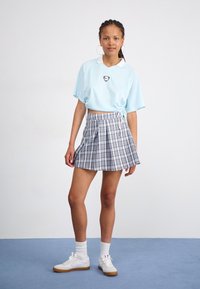 Polo de culoare albastră deschis, cu mânecă scurtă și guler alb, asortat cu o fustă plisată cu carouri gri. Completat cu adidași albi și șosete albe până la gleznă.