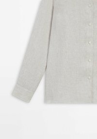 Chemise beige à manches longues avec de discrètes rayures verticales, fermeture à boutons et manches avec poignets, présentée sur fond blanc.