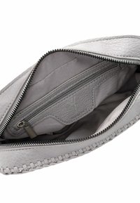 Interno di una borsa in pelle grigia con un comparto con cerniera, texture lisce e un design con bordo intrecciato. Presenta un'impronta del logo sulla fodera.