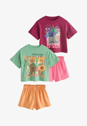 Two short-sleeve kids' tops with animal prints: one green with tiger and text, one burgundy with zebra and palm tree, paired with orange and pink shorts.