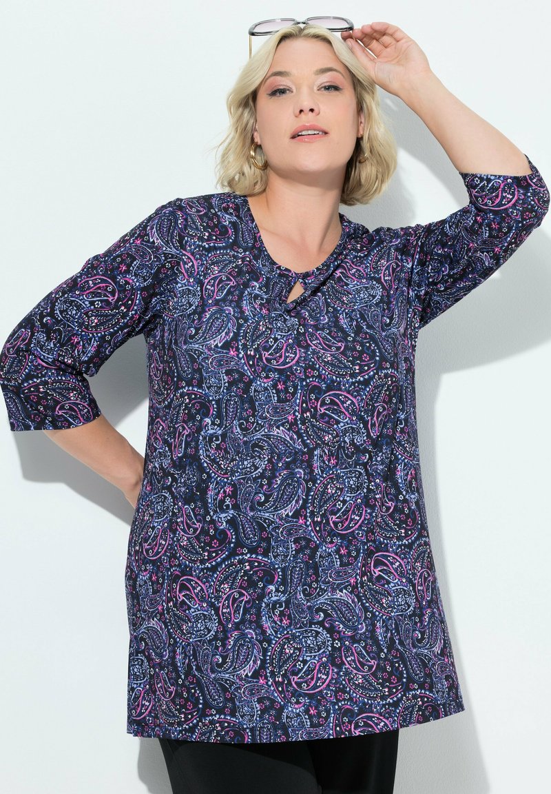 Tunic a maniche lunghe di colore blu navy con un motivo paisley rosa e blu, caratterizzata da un dettaglio a chiave nella scollatura e una vestibilità comoda.