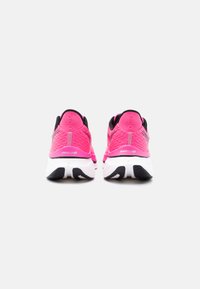 Φωτεινά ροζ παπούτσια για τρέξιμο με άσπρες σόλες και μαύρες λεπτομέρειες, σε θέα από πίσω σε απλό λευκό φόντο.