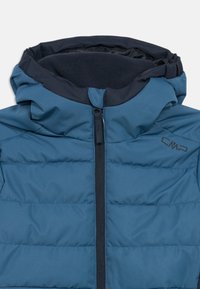Blue puffer jacket with a high collar, zip closure, and a soft fleece lining, featuring horizontal stitching and a CMP logo on the chest.