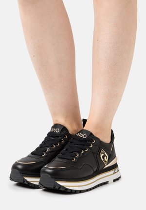 Sneaker in pelle nera con accenti dorati, design con lacci, suola bianca e nera e dettaglio del logo sul lato. Soprasso testurizzato e forma slanciata.