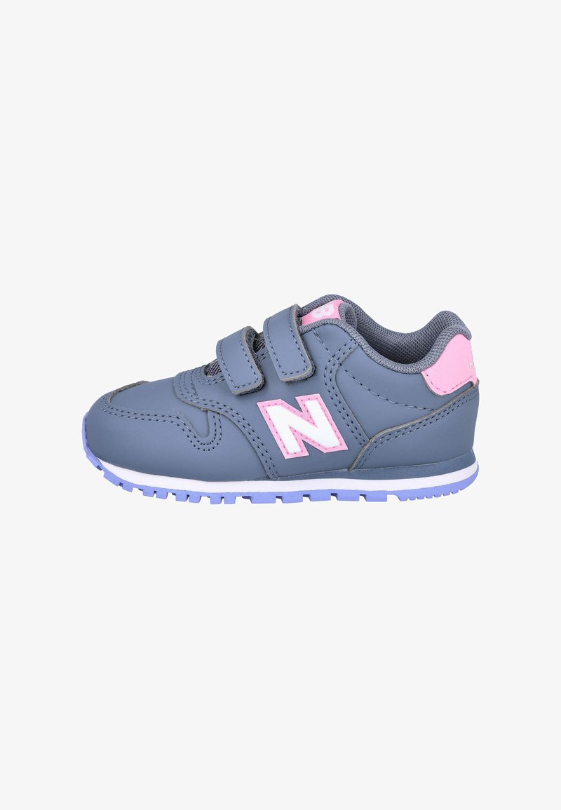 Zapatilla deportiva gris con acentos en rosa, dos tiras de velcro, suela de goma y parte superior texturizada hecha de material sintético.