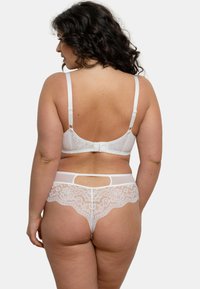 Ensemble de lingerie en dentelle blanche avec des bretelles ajustables. Le soutien-gorge présente un délicat revêtement en dentelle, tandis que le string a un design échancré avec des bords festonnés.