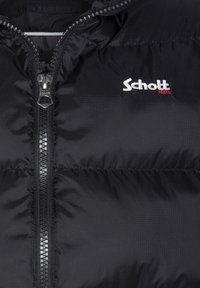 Giacca a vento nera con una texture liscia, dotata di una zip centrale, logo del marchio in bianco e cuciture rosse, e sezioni arricciate per l'isolamento.