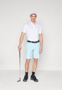 White polo shirt, light blue shorts, black belt, and black golf shoes. Character holds a golf club, wearing a white cap with logo.
