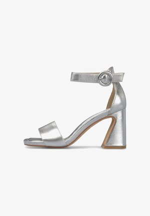Srebrny sandał na obcasie z teksturowanym metalicznym wykończeniem, otwarty czubek, pasek wokół kostki z okrągłą klamrą i geometryczny blokowy obcas.