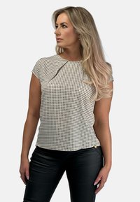 Beżowa bluzka z krótkim rękawem w kratę, z detalami w postaci fałd na przodzie oraz ozdobnym złotym guzikiem na dole.