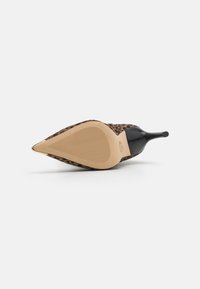 Escarpin à talon aiguille pointu au motif léopard, avec des accents noirs brillants et une semelle beige lisse avec une texture antidérapante.