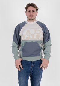 Felpa colorata con maniche raglan caratterizzata da blocchi di colore beige, grigio e verde. Include una tasca frontale e polsini a coste.